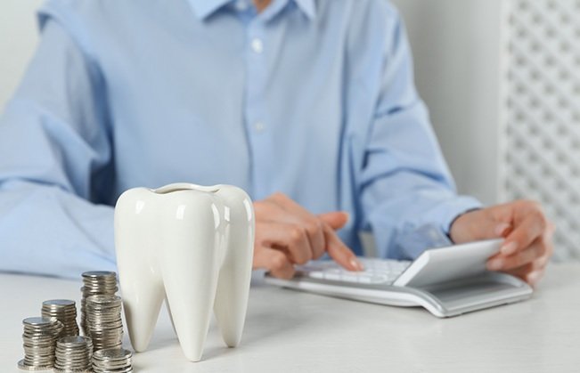 A woman using a calculator to confirm the cost of dental care 