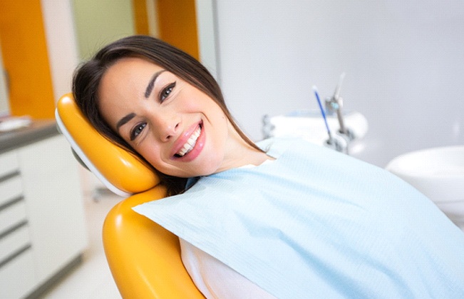Woman in dental chair leaning back and smiling