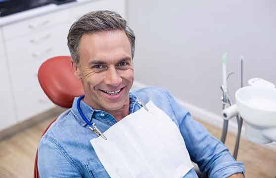 Man in denim jacket smiling in dental chair