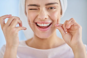 Woman flossing her teeth and smiling