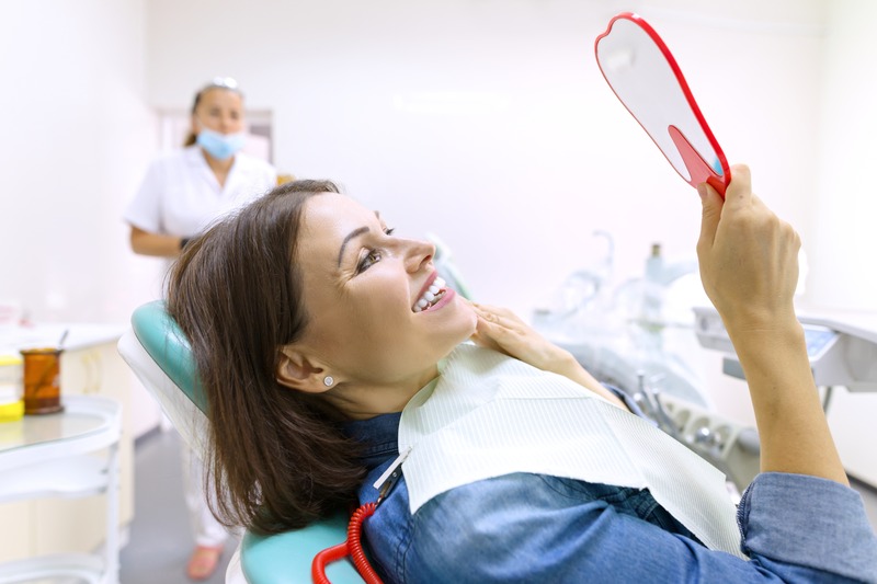 Patient smiling in mirror after having Invisalign attachments removed.